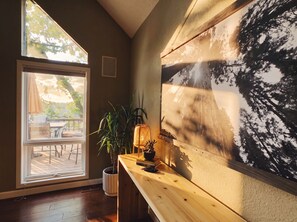 A room with a large window, a wooden desk, a potted plant, and a wall-mounted lamp. - Peaceful Lakefront Retreat with Private Dock, Fire Pit, Kayaks (Gravois Mills)
