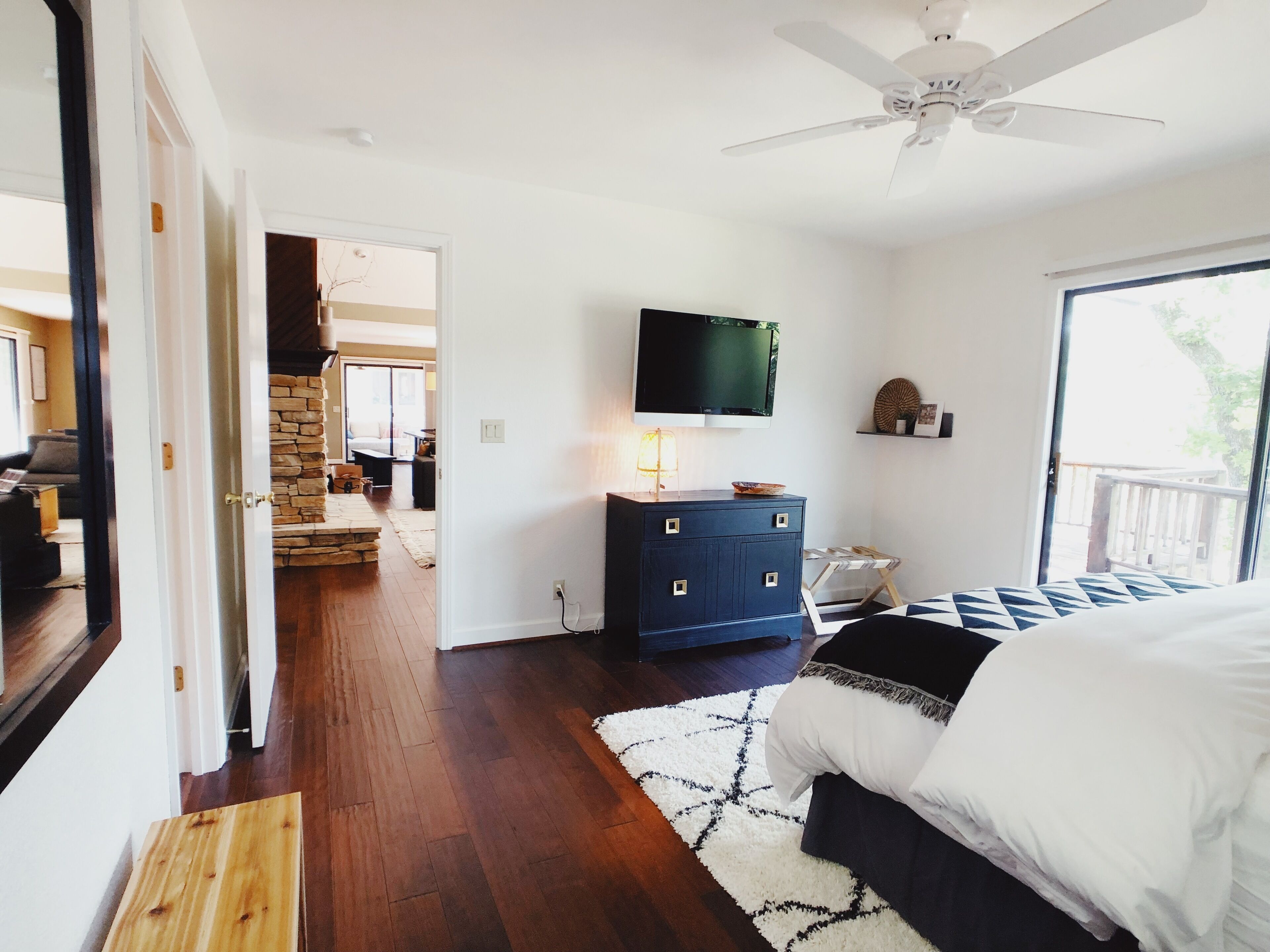 Une chambre à coucher comprenant un lit, une commode, un téléviseur et donnant sur l’extérieur.