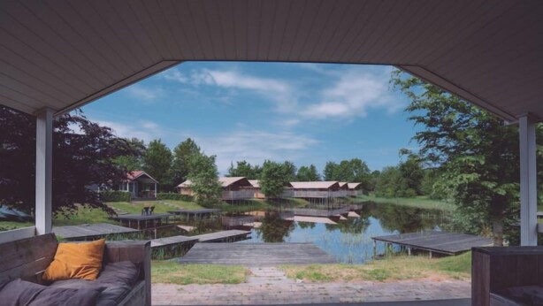 Un espacio al aire libre techado con vistas a un lago y cabañas.