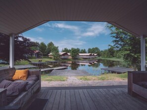 Área externa coberta com vista para um lago e cabanas.