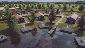 Un conjunto de cabañas con terrazas de madera, rodeadas de un paisaje cubierto de césped y árboles.