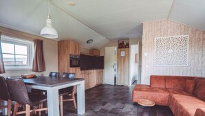 Una cocina moderna con armarios de madera, una mesa de comedor con sillas, un televisor y un sofá.