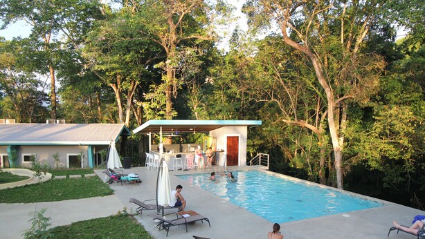 A backyard with a swimming pool, lounge chairs, and a covered patio area. - Téva Eco Retreat - Hostel (Quepos)