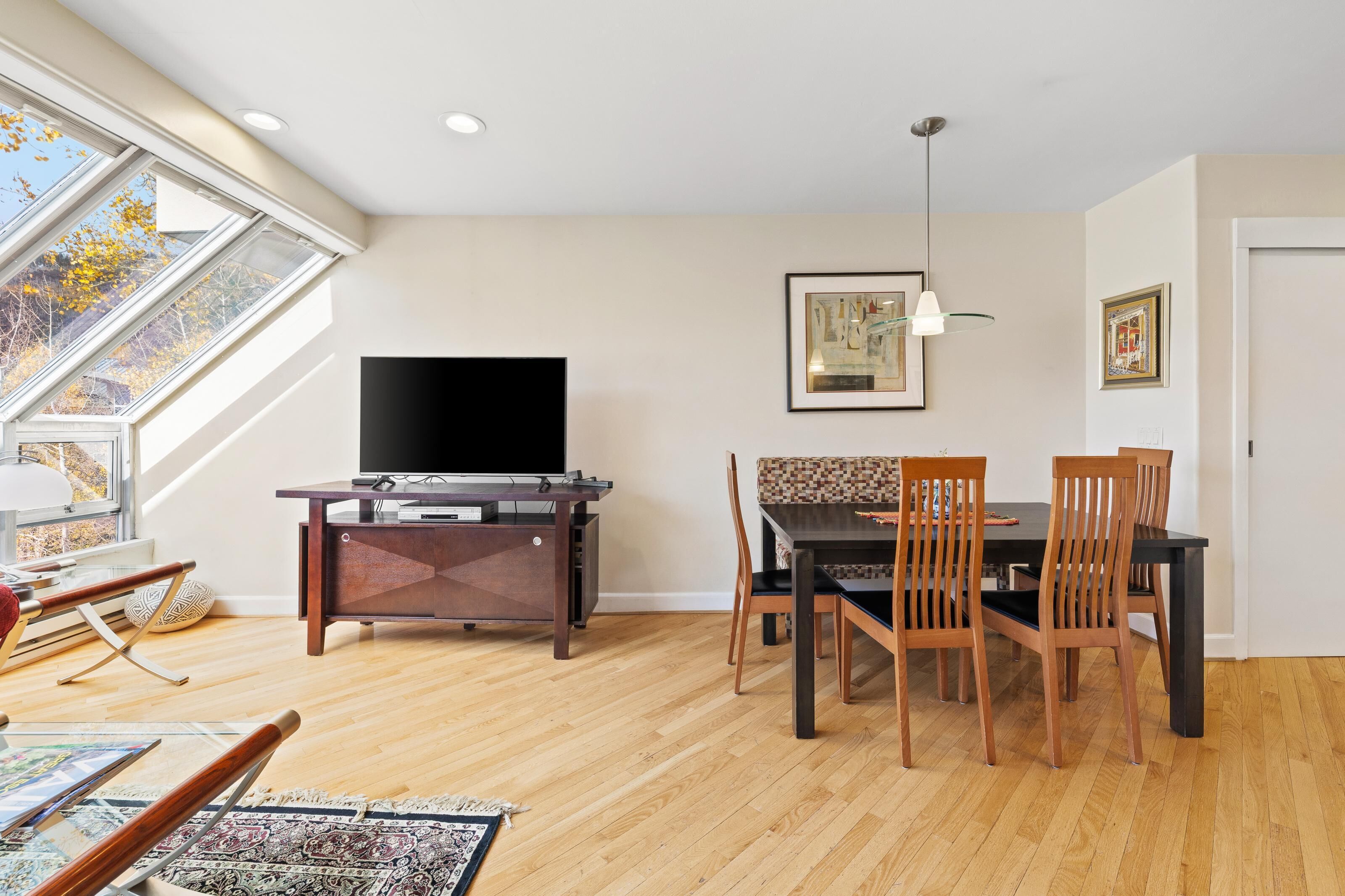 A dining area with a TV, wooden chairs, and a table.