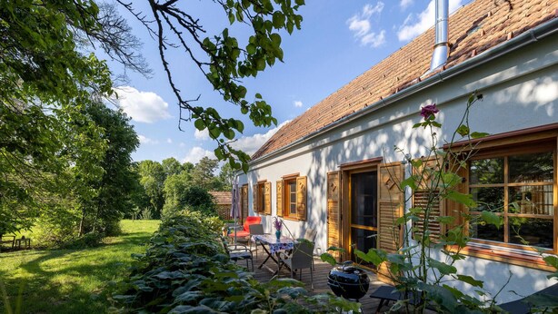 A house with a white exterior, wooden shutters, and a tiled roof.