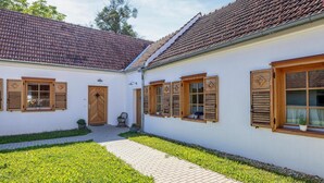 A traditional building with a tiled roof, wooden shutters, and a paved courtyard.