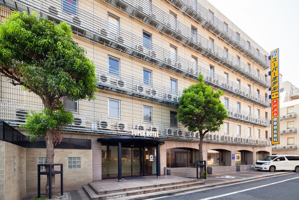 A multi-story hotel with a modern facade, featuring a prominent entrance with a covered area and a large tree in front. - Super Hotel Inn Kurashiki Mizushima (Kurashiki)