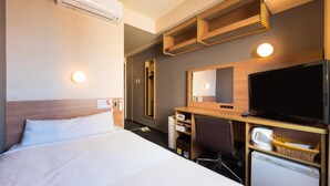 Ett hotellrum med en säng, ett skrivbord med en dator, en tv och en luftkonditioneringsanläggning.