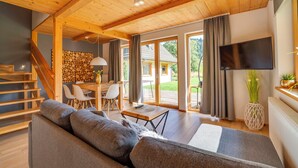 A spacious living area with a wooden ceiling, a large sofa, a dining table with chairs, and a TV mounted on the wall. - Chaty Pod Beskidkiem by Interhome (Szczyrk)