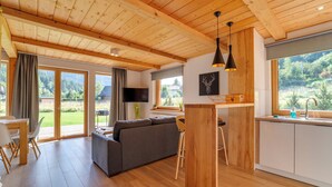 A modern interior with a wooden ceiling, a living area with a sofa, a dining table, and a kitchen with a window view. - Chaty Pod Beskidkiem by Interhome (Szczyrk)