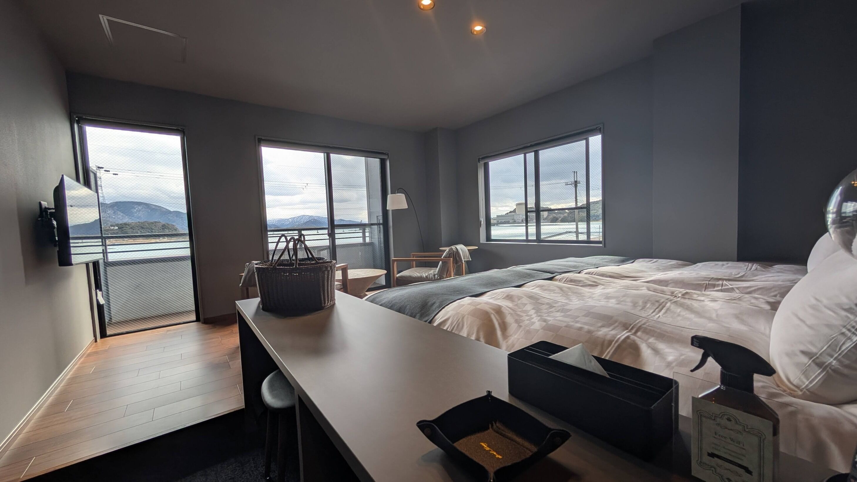 Ein modernes Hotelzimmer mit einem großen Bett, einem Schreibtisch, einem Sessel, einem Fernseher und Blick auf das Meer.