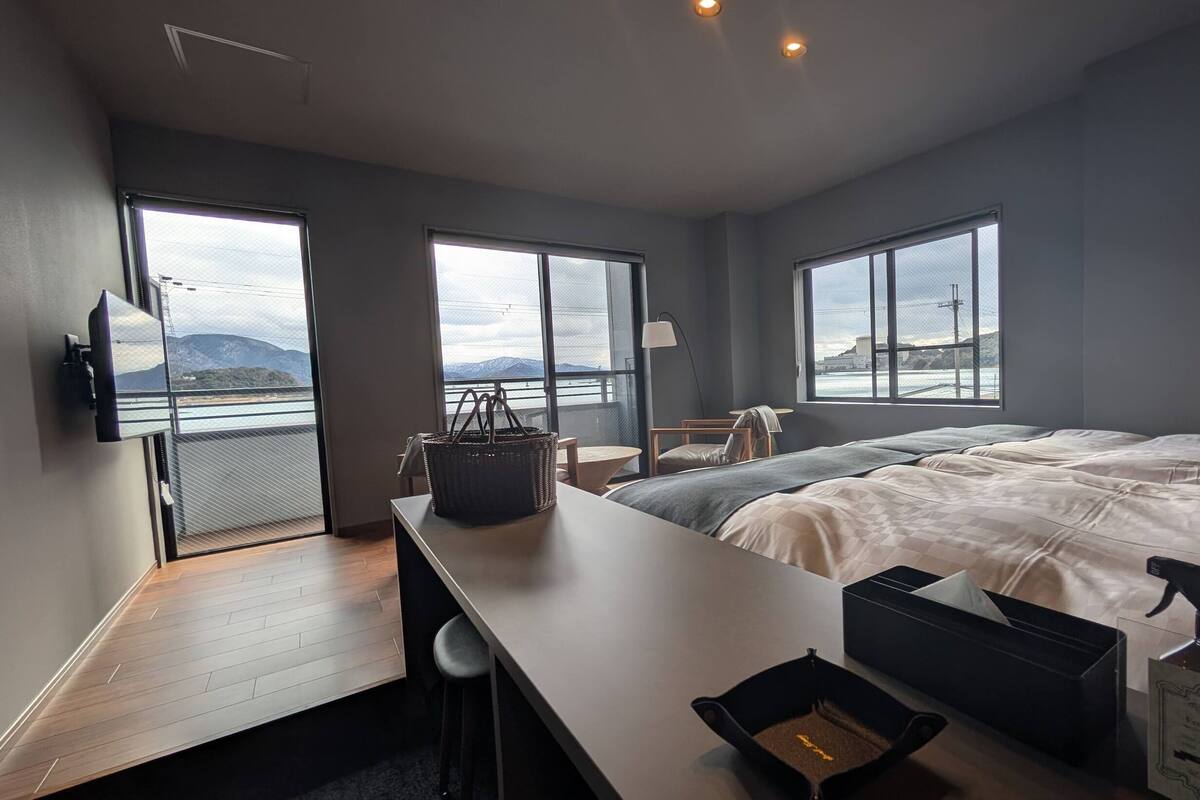 Una camera d'albergo moderna con un letto grande, una scrivania, una sedia, una televisione e vista sul mare.