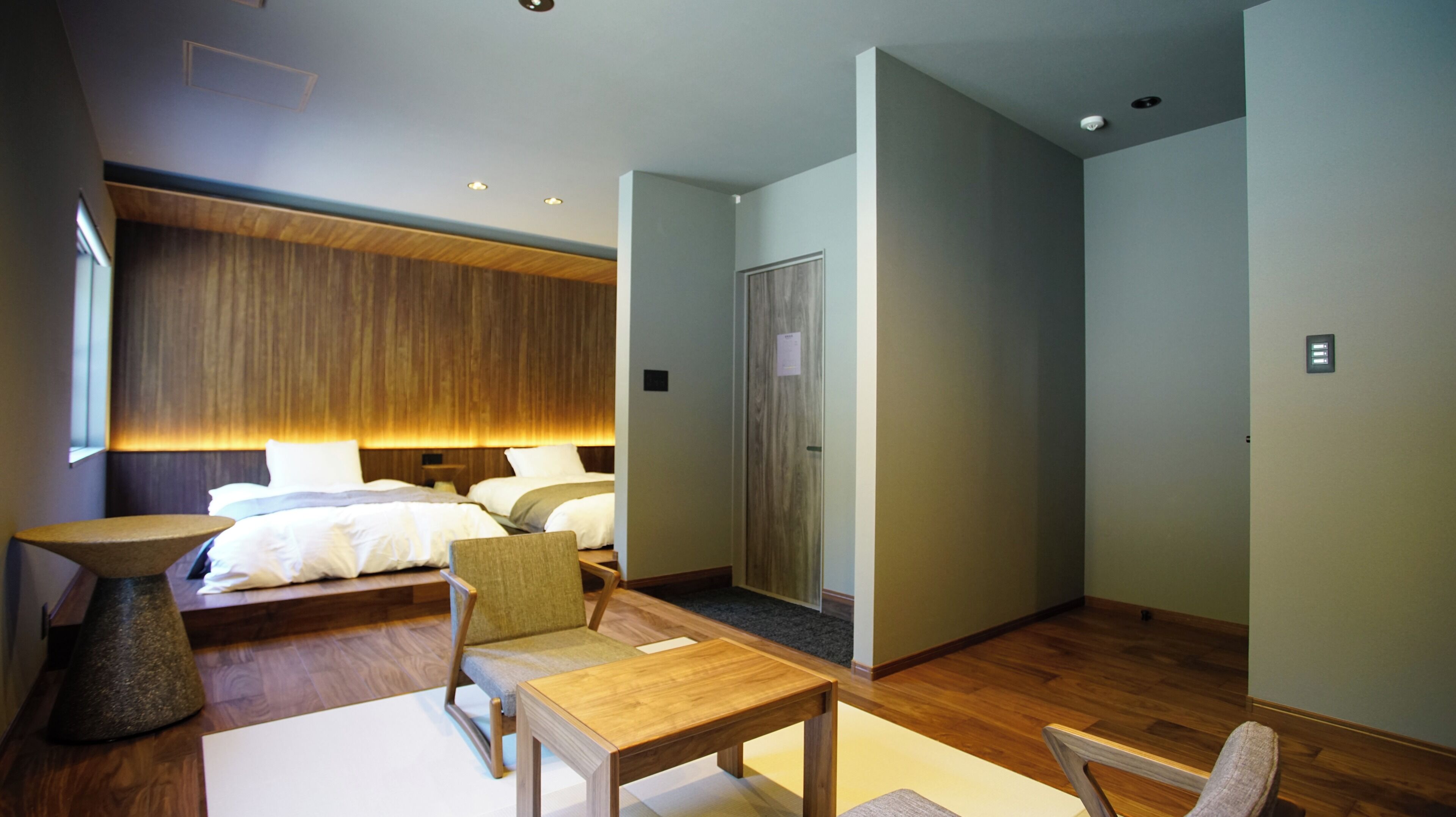 Ein modernes Hotelzimmer mit einem großen Bett, einem Schreibtisch, einem Stuhl und einem kleinen Tisch.