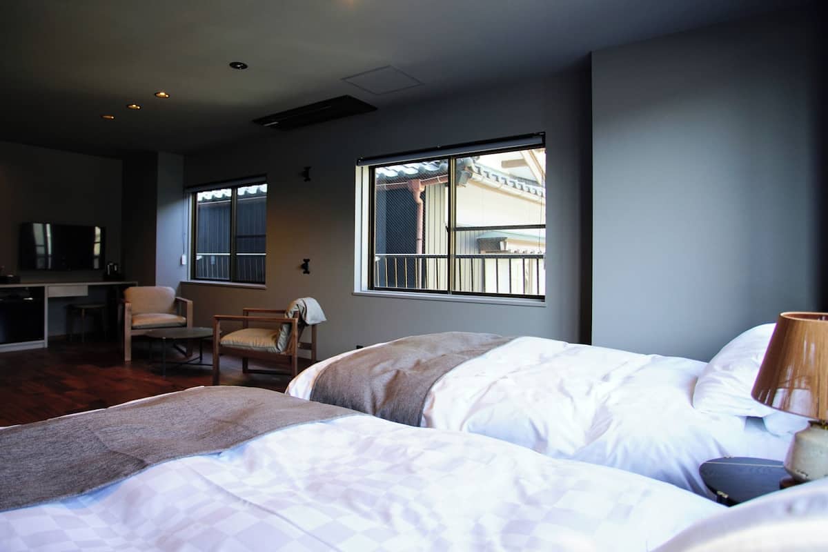 Ein Hotelzimmer mit zwei Betten, einem Schreibtisch, einem Stuhl und einem Fenster mit Blick.