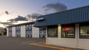 A building with a reception area, marked by a sign, and a parking lot in front. - Travelodge by Wyndham Blairmore (Blairmore)