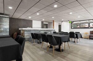 Una sala de conferencias moderna con una mesa larga, sillas negras y un mostrador de recepción blanco.