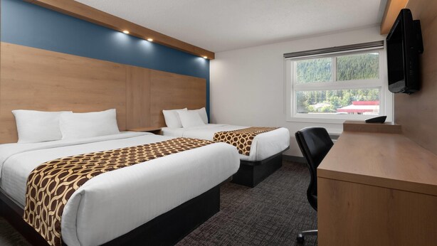 A hotel room with two beds, a desk, and a TV. - Travelodge by Wyndham Blairmore (Blairmore)