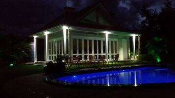 A covered outdoor area with a pool, chairs, and a table.