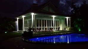 Ein überdachter Außenbereich mit Pool, Stühlen und einem Tisch.