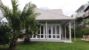 A house with a tiled roof, a covered porch, and a well-maintained lawn. - Casa da Piscina Bento Gonçalves (Bento Gonçalves)