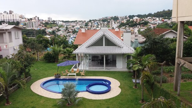 A residential property with a swimming pool, a covered patio, and a view of a cityscape. - Casa da Piscina Bento Gonçalves (Bento Gonçalves)