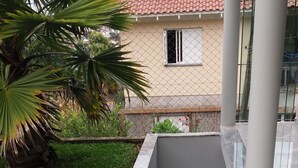 A concrete staircase with a metal railing, surrounded by a grassy area and a building with a tiled roof. - Casa da Piscina Bento Gonçalves (Bento Gonçalves)