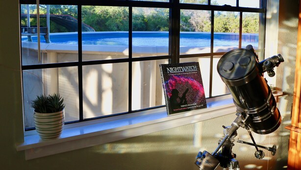 A telescope on a tripod, a book titled "Nightwatch," and a potted plant on a windowsill. - Beautiful Zen Temple Home on Canyon Lake! (Canyon Lake)