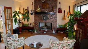 A living room with a brick fireplace, floral armchairs, a round coffee table, and a large plant. - Beautiful Zen Temple Home on Canyon Lake! (Canyon Lake)
