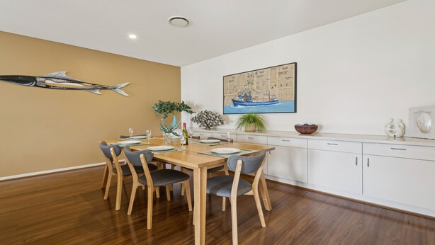 A dining area with a wooden table and chairs, a map on the wall, and a decorative fish sculpture. - Koonya Sur Mer Coastal Sorrento Escape (Sorrento)