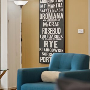 Une pièce avec un fauteuil bleu et un mur sur lequel figure une liste de noms et de lieux.