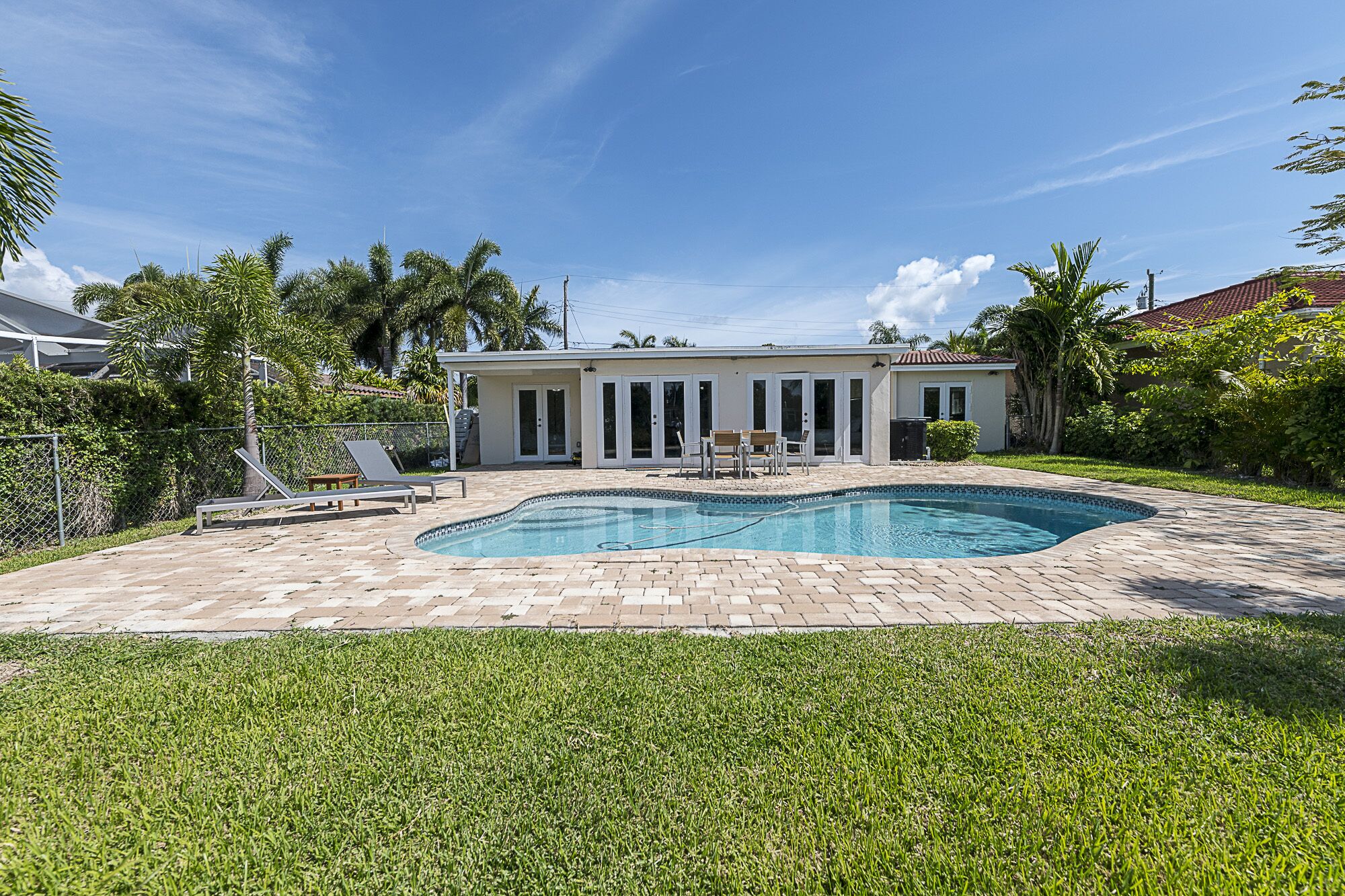 Ein Haus mit Swimmingpool, überdachter Terrasse und Rasen.