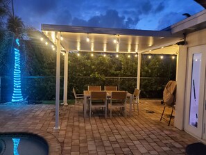 Relax in a serene outdoor space with a covered seating area, brick floor, and a small pool.