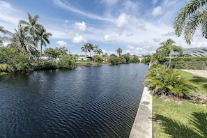 Overlooking a serene waterfront, this property offers a tranquil atmosphere surrounded by lush greenery and well-manicured lawns.