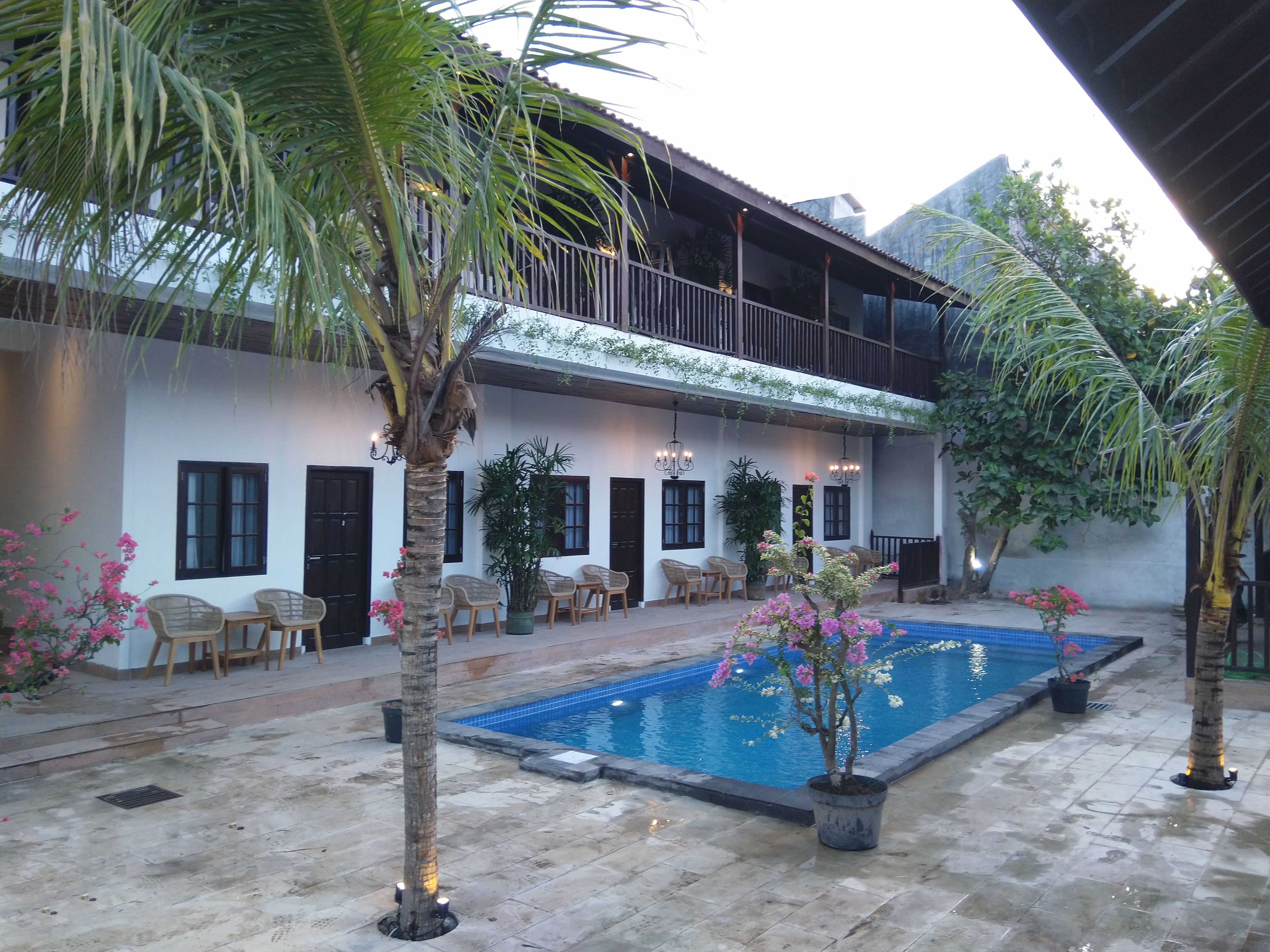 A courtyard with a swimming pool, outdoor seating, and a building with a balcony.
