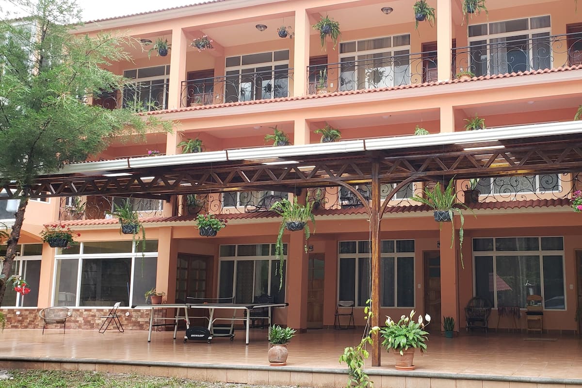 Un edificio de varios pisos con balcones, plantas en macetas y mobiliario exterior.