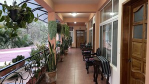 A corridor with potted plants, wooden benches, and a door. - Jabel Tinamit Hotel & Villas (Panajachel)