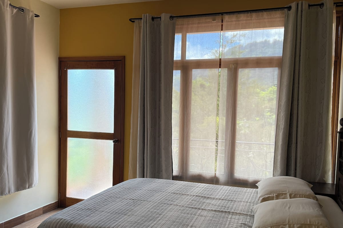 Un dormitorio con cama, cortinas y ventana.