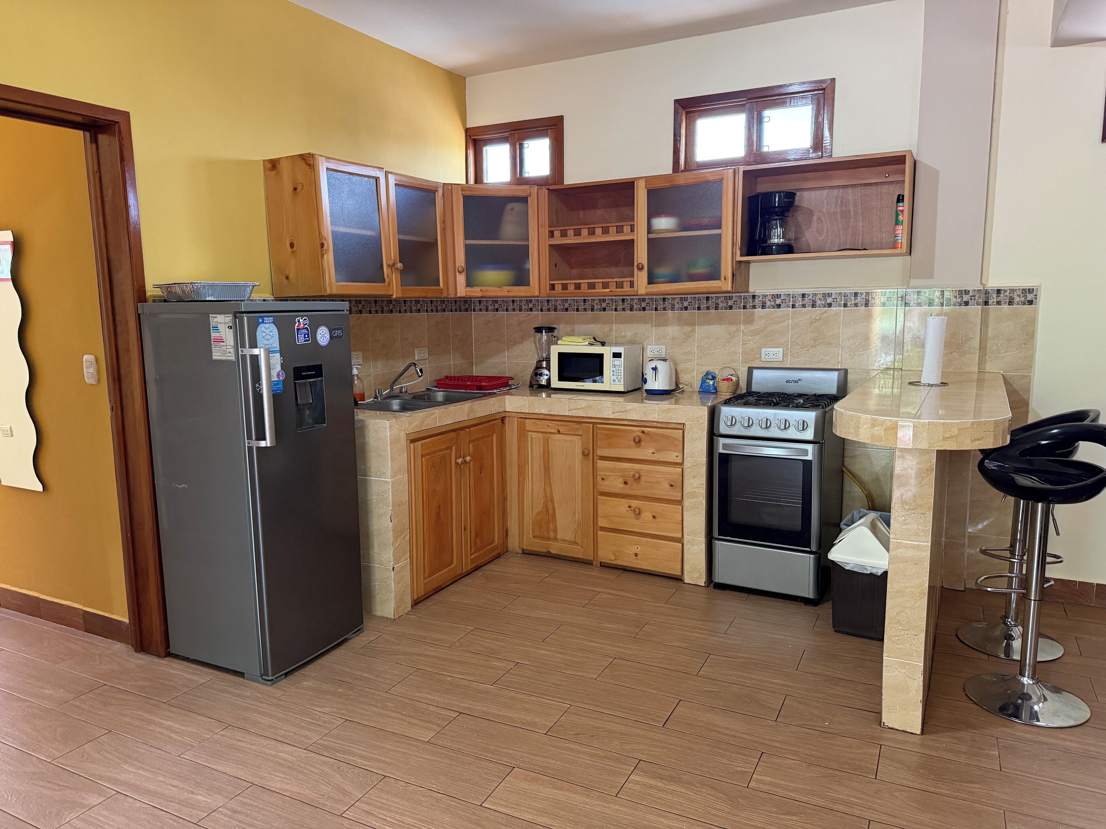 Una cocina con armarios de madera, refrigerador, microondas, estufa y lavaplatos.