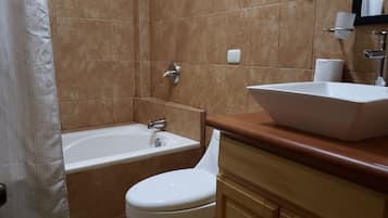 Un baño con bañera, inodoro y lavamanos.