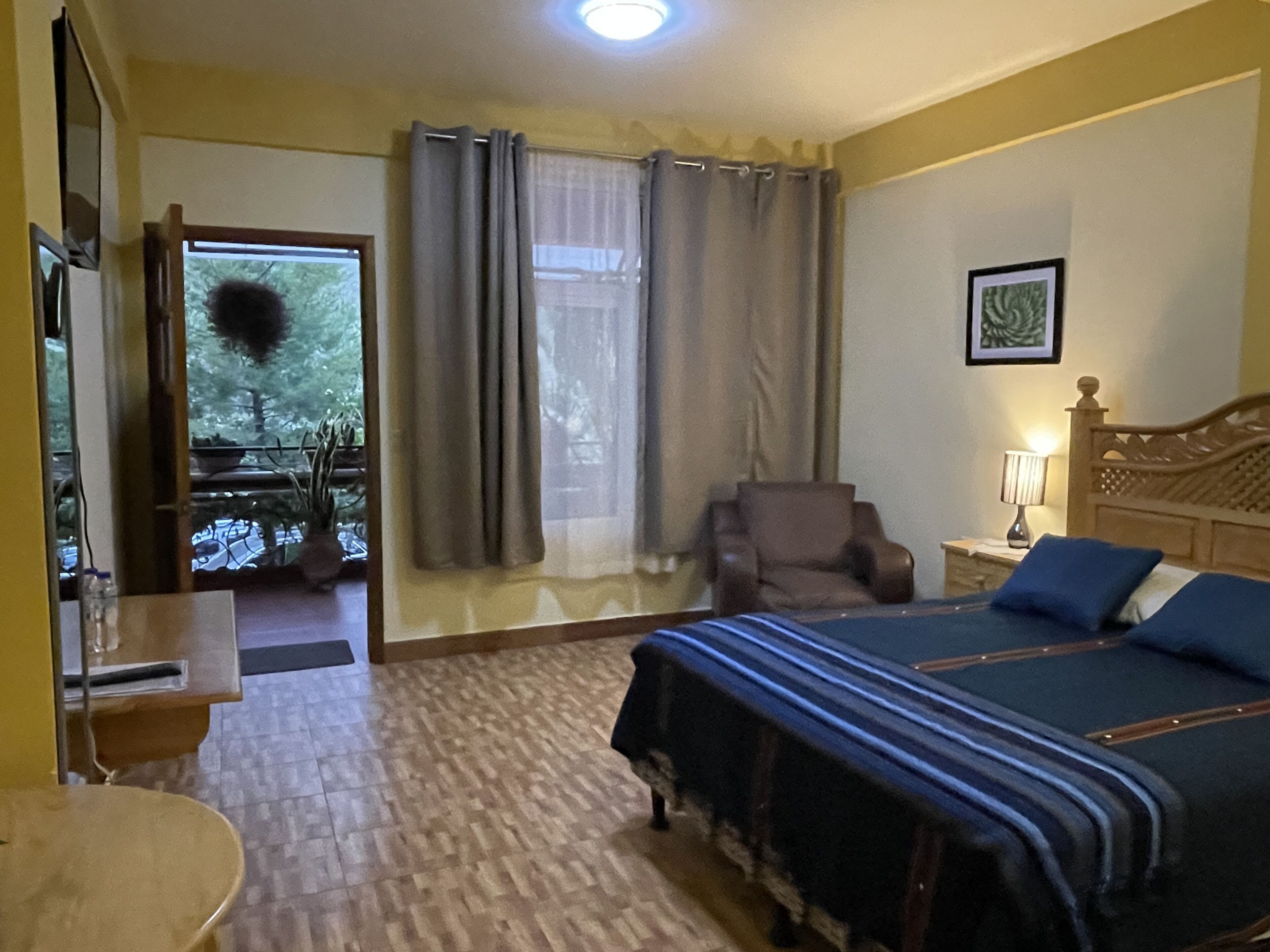 Et hotelværelse med seng, stol, skrivebord og et vindue med gardiner.