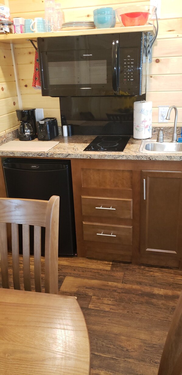A compact kitchen with a microwave, coffee maker, and a sink.