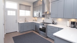 Une cuisine moderne avec des meubles gris, une cuisinière en acier inoxydable et un four encastré.