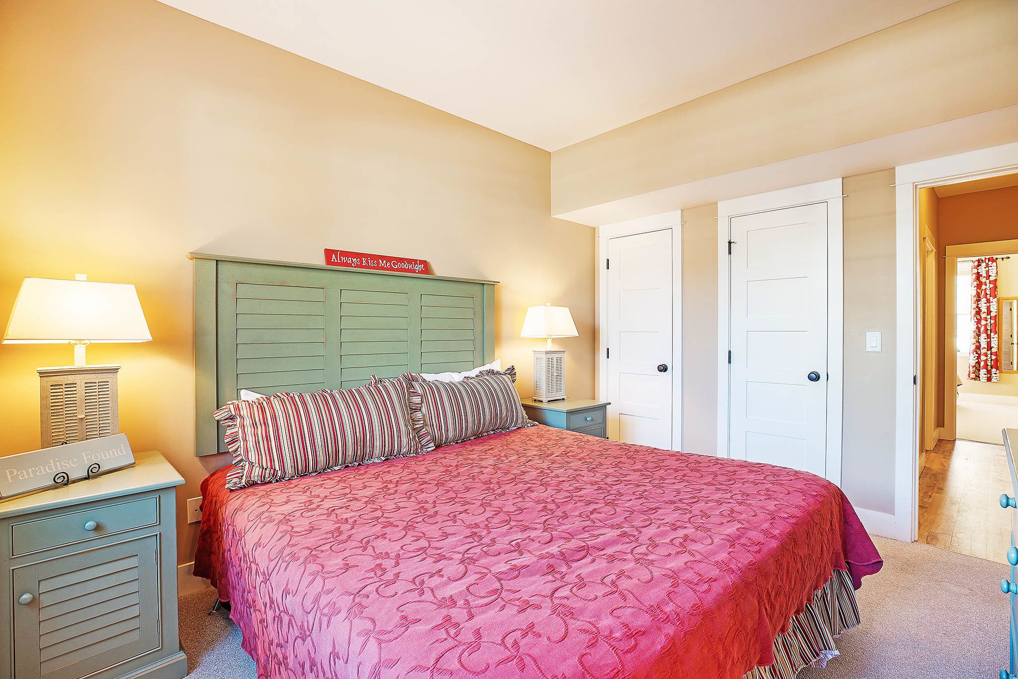 A bedroom with a bed, two nightstands, a dresser, and a door.