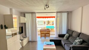 A modern living room with a sectional sofa, a coffee table, and a TV on a cabinet. - Apartment Los Molinos (Puerto de Naos)