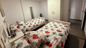 A bedroom with two single beds, a wardrobe, a mirror, and a door leading to another room. - Apartment Los Molinos (Puerto de Naos)