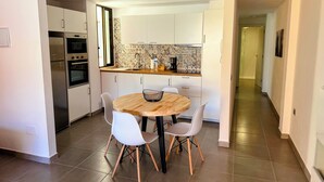 A compact kitchen with white cabinets, a wooden dining table, and two white chairs. - Apartment Los Molinos (Puerto de Naos)