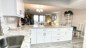A modern kitchen with white cabinetry, a marble countertop, and a built-in sink. - Direct Oceanfront Condo Renovated & New Furniture-Pools,Hot Tub, Sauna,Free wifi (Myrtle Beach)