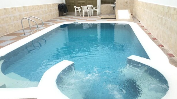 A swimming pool with a hot tub, surrounded by a tiled deck and a few chairs. - Villa Ensueño - House with Pool & Hot Tub (Flandes)