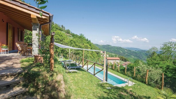 Ein Poolbereich mit Holzterrasse und Liegestühlen, umgeben von üppiger Vegetation und sanften Hügeln im Hintergrund.