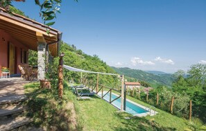 Ein Poolbereich mit Holzterrasse und Liegestühlen, umgeben von üppiger Vegetation und sanften Hügeln im Hintergrund.